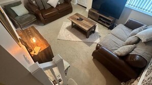 A living room with a brown sofa, a coffee table, a TV, and a lamp. - Cosy Birmingham Retreat Near City Centre, Airport (Birmingham)