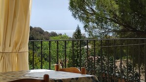 A balcony with a table and chairs, overlooking a scenic view of trees and a distant landscape. - Villa La Dipladenia in Costa Rei (Muravera)
