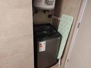 Efficient laundry facilities with a front-loading washing machine and a convenient towel rack.