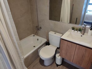 Bathroom features a bathtub, toilet with bidet, and sink with mirror.