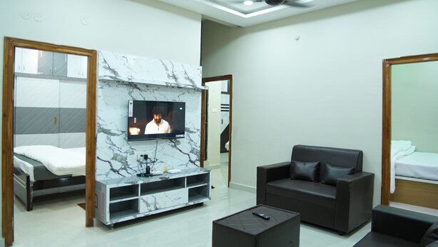 A modern living room with a TV, sofa, and a fireplace. - Hiraa inn Studio Apartments (Kurnool)