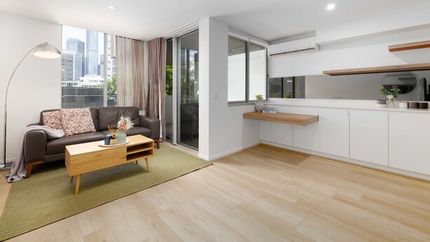 Un apartamento moderno con sala de estar, cocina y un gran ventanal corredizo hacia el exterior.