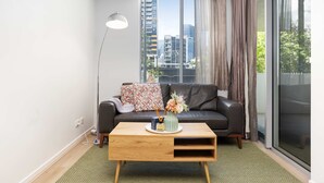Una sala moderna con un sofá, una mesa de centro y un ventanal con vista a la ciudad.