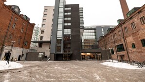 Un edificio moderno con fachadas de ladrillo y vidrio, una escalera central y suelo cubierto de nieve.