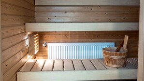 Una sauna de madera con un banco, un balde y una cuchara de madera.