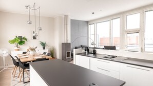 Cocina moderna con una isla grande, armarios blancos y un amplio ventanal que proporciona luz natural.