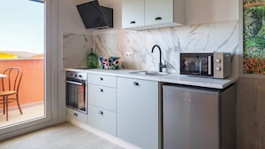 Cocina moderna con horno integrado, microondas y lavabo. Una ventana ofrece vistas al exterior.