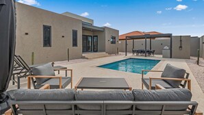 A modern outdoor pool area with lounge chairs and a dining table. - Safir 40 (Noord)