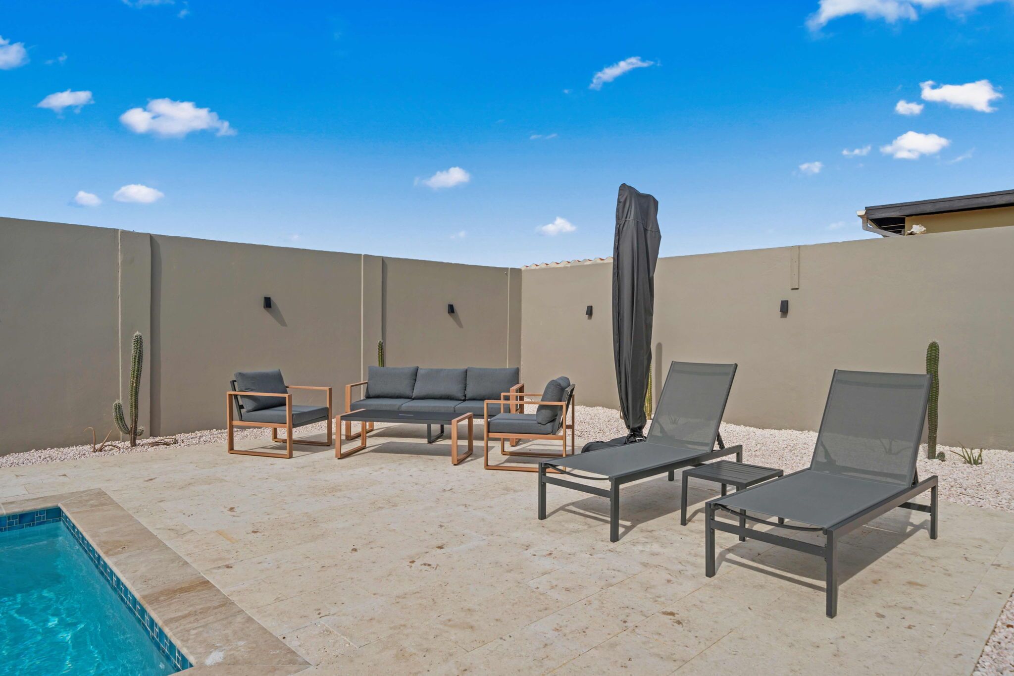 A poolside area with lounge chairs, a small pool, and cacti.