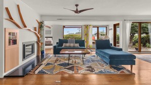A modern living room with a sofa, coffee table, and a fireplace. - Boho-Style Point Loma Retreat, Large Outdoor Deck (San Diego)