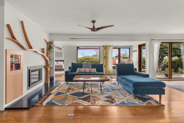 A modern living room with a sofa, coffee table, and a fireplace. - Boho-Style Point Loma Retreat, Large Outdoor Deck (San Diego)
