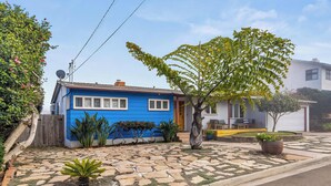 A blue house with a stone patio, a small tree, and a potted plant. - Boho-Style Point Loma Retreat, Large Outdoor Deck (San Diego)