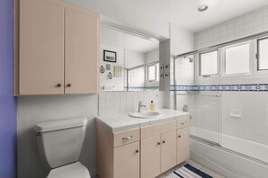 A modern bathroom with a toilet, sink, vanity, mirror, and shower. - Boho-Style Point Loma Retreat, Large Outdoor Deck (San Diego)