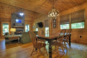 A wooden cabin interior with a dining table, chairs, a fireplace, and a television. - Smokey's Place | $189 Off Your Stay! (Blue Ridge)