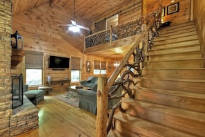 A log cabin interior with a wooden staircase, a ceiling fan, a flat-screen TV, and a cozy seating area. - Smokey's Place | $189 Off Your Stay! (Blue Ridge)