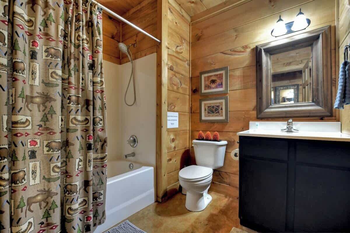 A wooden cabin bathroom with a bathtub, toilet, and sink.
