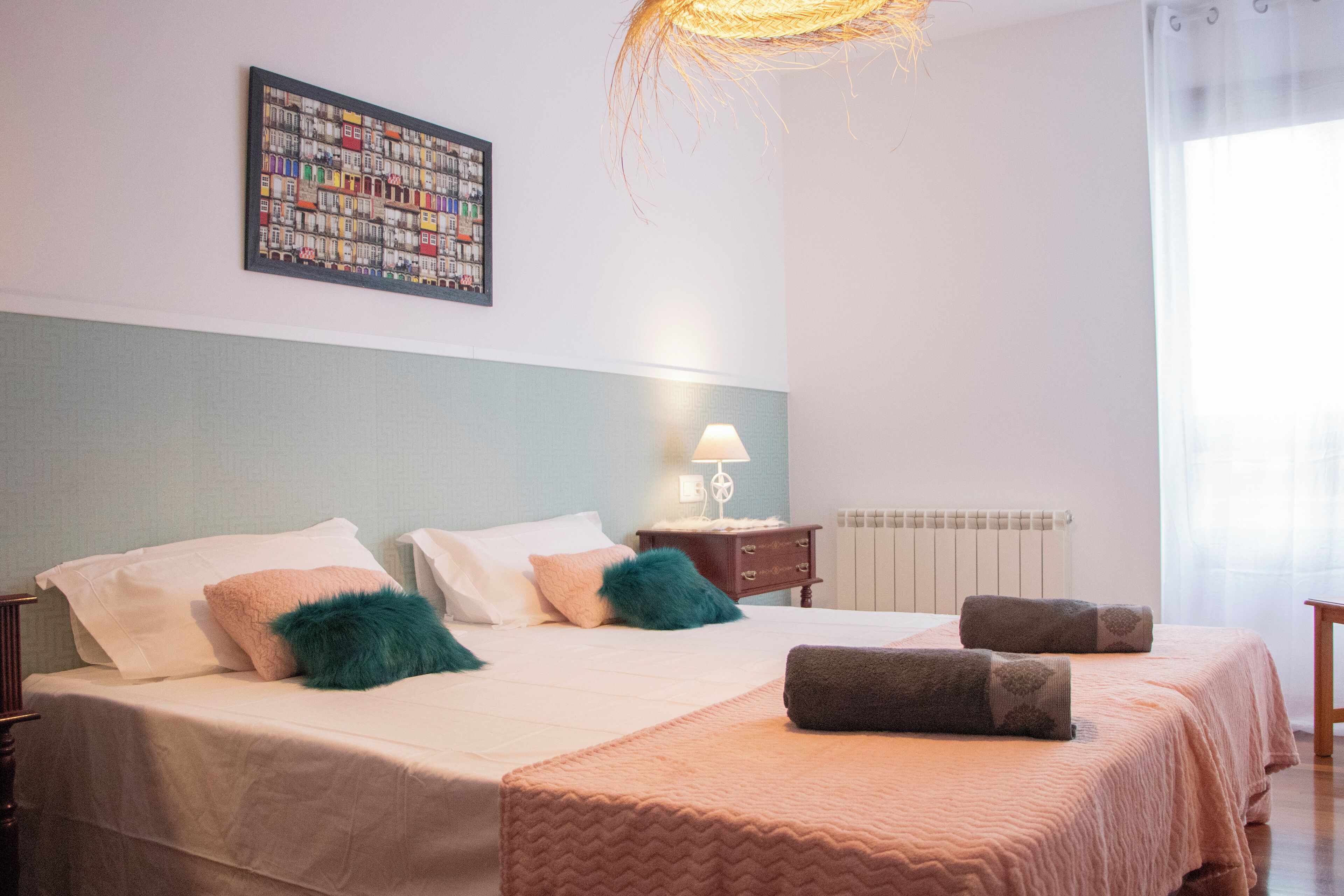 A neatly arranged bedroom with a bed, pillows, a bedside table with a lamp, and a radiator.