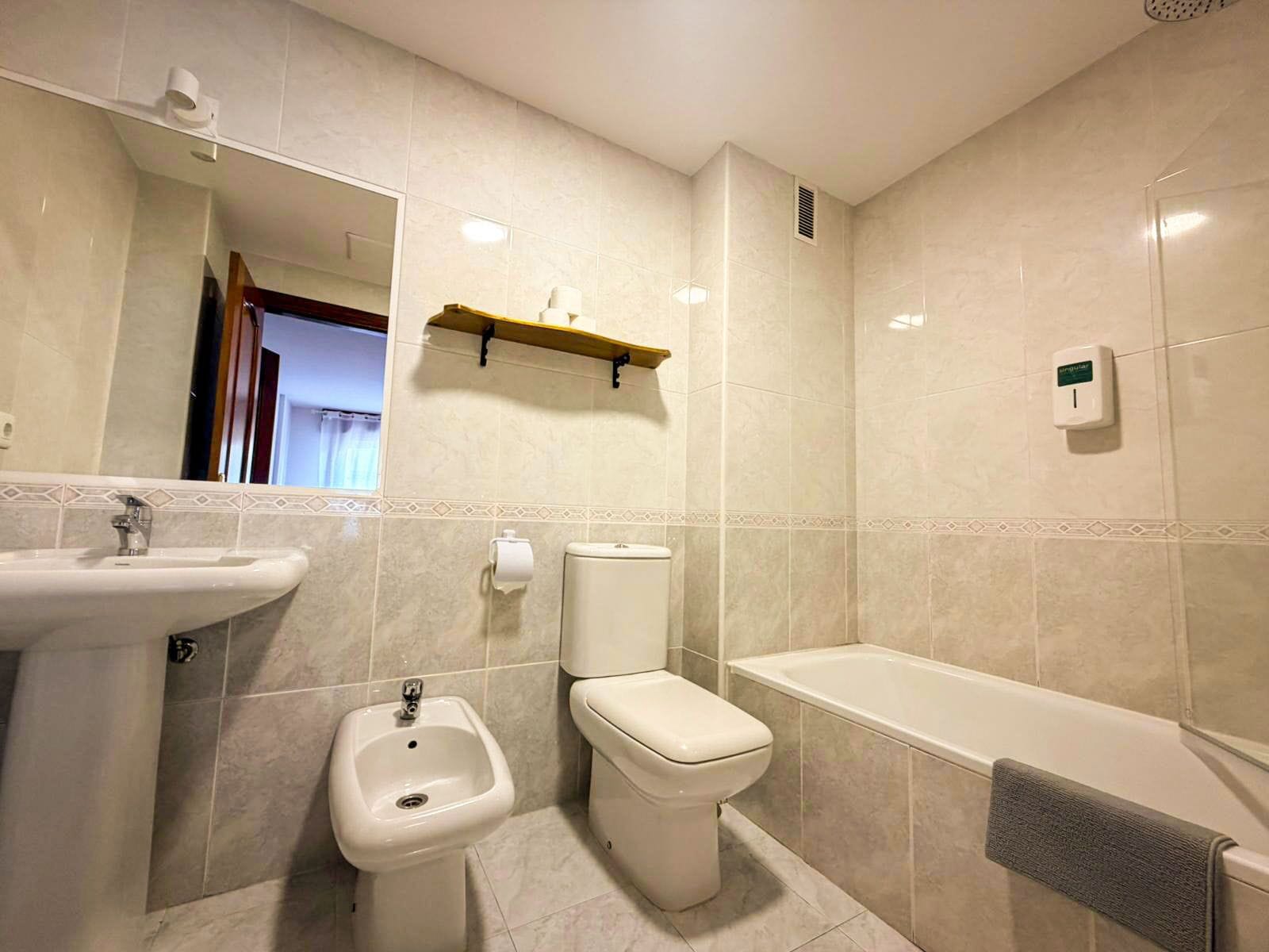 A bathroom with a sink, bidet, toilet, and bathtub.