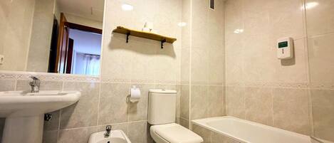 A bathroom with a sink, bidet, toilet, and bathtub.