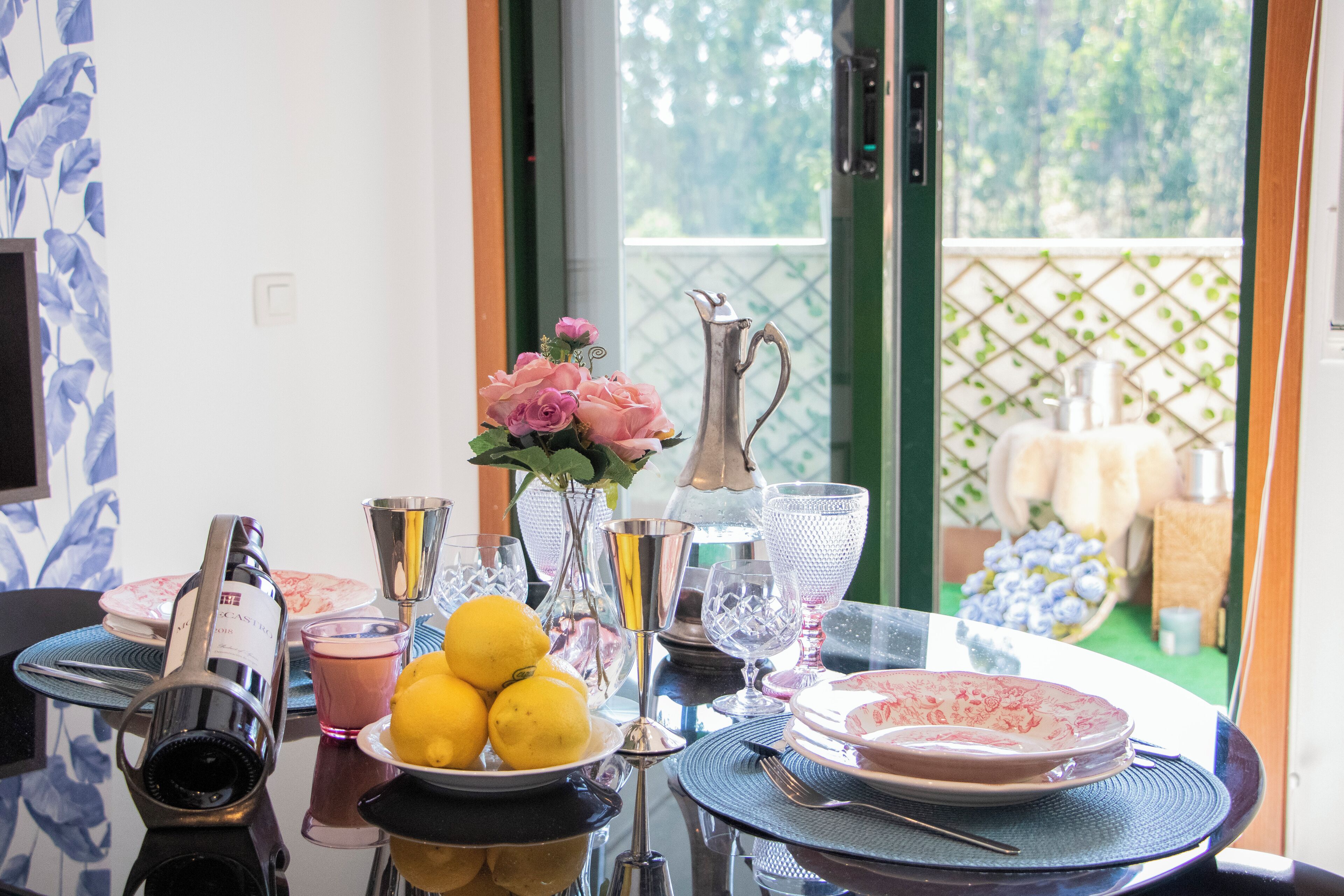 A dining table with a variety of glassware, a pitcher, and a plate of lemons.