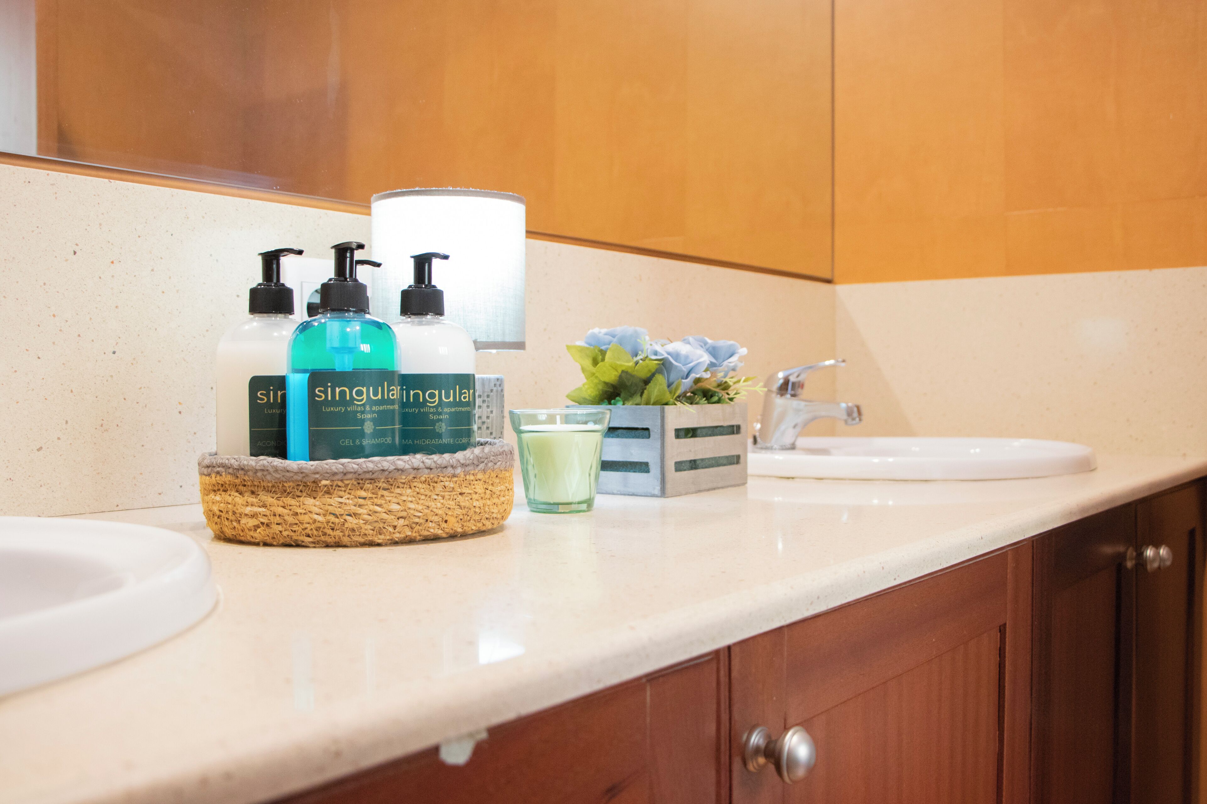 A bathroom with a sink, a mirror, and toiletries including a bottle of Singulair, a bottle of lotion, and a glass of water.