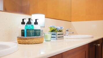 A bathroom with a sink, a mirror, and toiletries including a bottle of Singulair, a bottle of lotion, and a glass of water.