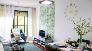 Un salon comprenant un coin repas, un téléviseur et une horloge murale.