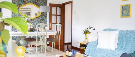 A living room with a dining area, a sofa, a coffee table, and a mirror.