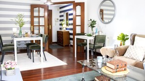 Un salon moderne avec un coin repas, caractérisé par un mur à rayures, des portes en bois et un miroir rond.
