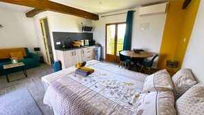 A bedroom with a bed, a sofa, a small table, a kitchenette, and a dining area. - La Maison des Crêtes - Studio with view of the Vercors mountains (Parnans)