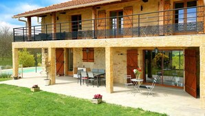 A two-story stone house with a balcony, outdoor seating area, and a swimming pool in the background. - La Maison des Crêtes - Studio with view of the Vercors mountains (Parnans)