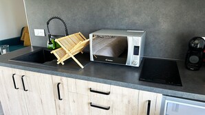 A kitchen with a microwave, a kettle, and a wooden drying rack. - La Maison des Crêtes - Studio with view of the Vercors mountains (Parnans)