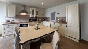 A modern kitchen with white cabinetry, a central island, and built-in appliances. - Beautiful stone barn with year-round heated pool<br>Magnificent setting in the heart of the Perche region (Belforêt-en-Perche)