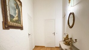 A hallway with wooden flooring, a white door, and a console table with a candelabra. - Beautiful stone barn with year-round heated pool<br>Magnificent setting in the heart of the Perche region (Belforêt-en-Perche)