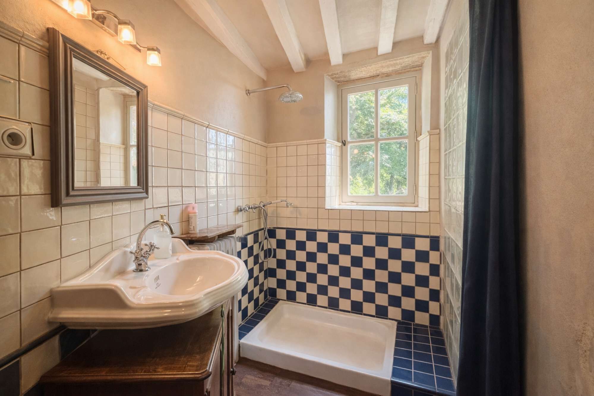 A bathroom with a white sink, a bathtub, and a window.