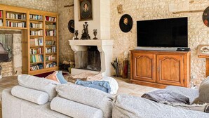 Ein gemütliches Wohnzimmer mit Kamin, einer großen Bücherwand, einem Fernseher und einer Steinwand.