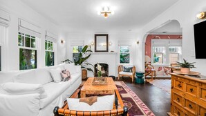 A spacious living room with a white sofa, a wooden coffee table, and a fireplace.
