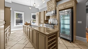 A modern kitchen with a central island, built-in oven, and a refrigerator.