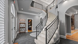 A grand staircase with a black railing, leading to an upper floor.