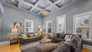 A living room with two sofas, a coffee table, and a patterned rug. There are two side tables with lamps and a ceiling light fixture.