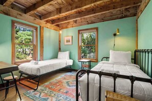 A room with two beds, a wooden ceiling, large windows, a small table, and a colorful rug. - Private Saltwater Pool, Game Room, near Beaches! (Barnstable)