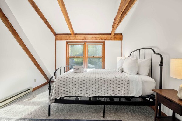 A bedroom with a bed, a nightstand, a window, and wooden beams on the ceiling. - Private Saltwater Pool, Game Room, near Beaches! (Barnstable)