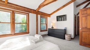 Une chambre à coucher avec un lit, une commode, une lampe et un téléviseur.