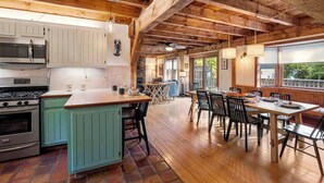 Une cuisine rustique avec des poutres en bois, un îlot central et un coin repas offrant une vue agréable.