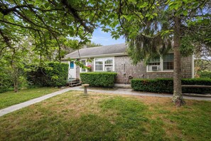 Une maison à deux étages avec un jardin devant, un petit porche et un garage.