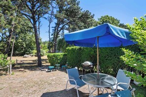 An outdoor patio with a blue umbrella, metal chairs, and a table. - Studio, Walk to Nauset Beach! (Orleans)
