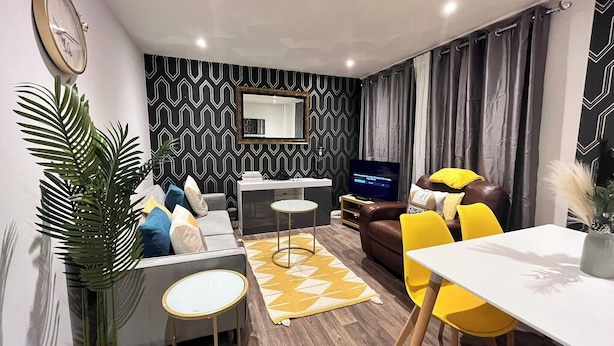Una sala de estar moderna con un sofá, una mesa de centro, un televisor y un comedor con sillas.