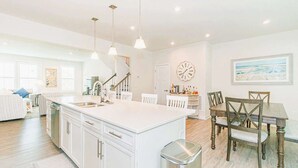 A spacious kitchen with a large island, white cabinetry, and pendant lighting. - Family Fun house at Barefoot Resort & Golf (North Myrtle Beach)