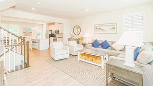 A spacious living area with a sofa, armchairs, a coffee table, and a kitchen in the background. - Family Fun house at Barefoot Resort & Golf (North Myrtle Beach)