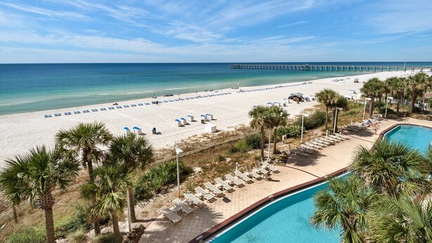 A beach resort with a pool, lounge chairs, and a pier in the background. - 401E Beach Service Included! End Unit! (Panama City Beach)